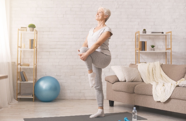 A senior does some stretching exercises in her living room.