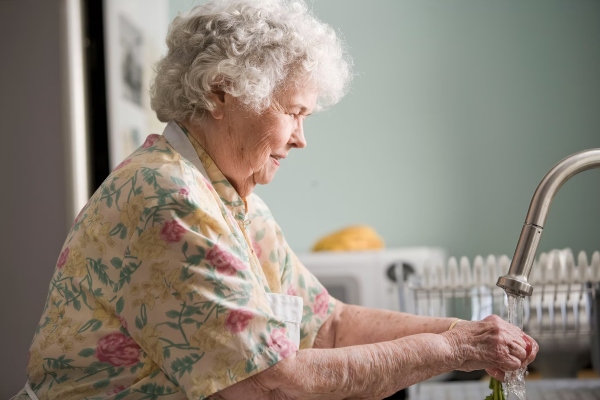 An elderly lady washes her hand to keep up her hygiene. 