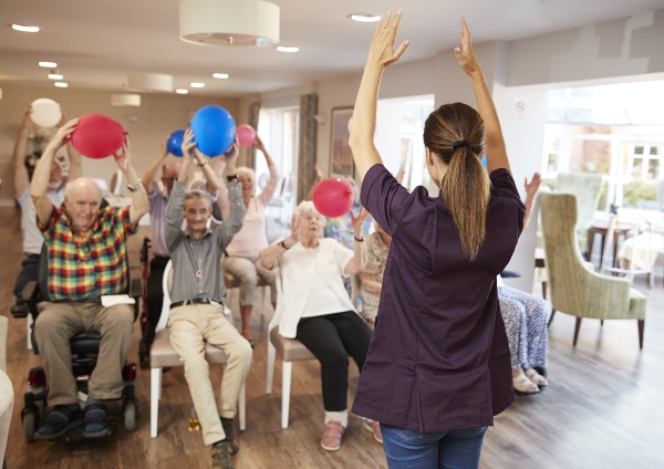 An instructor leads a group exercise class for seniors.